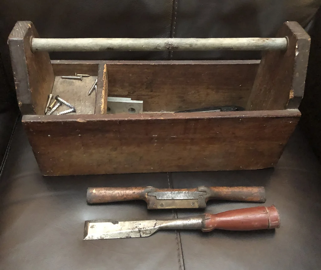 A wooden tool tote with a chisel and a spokeshave lying beside it
