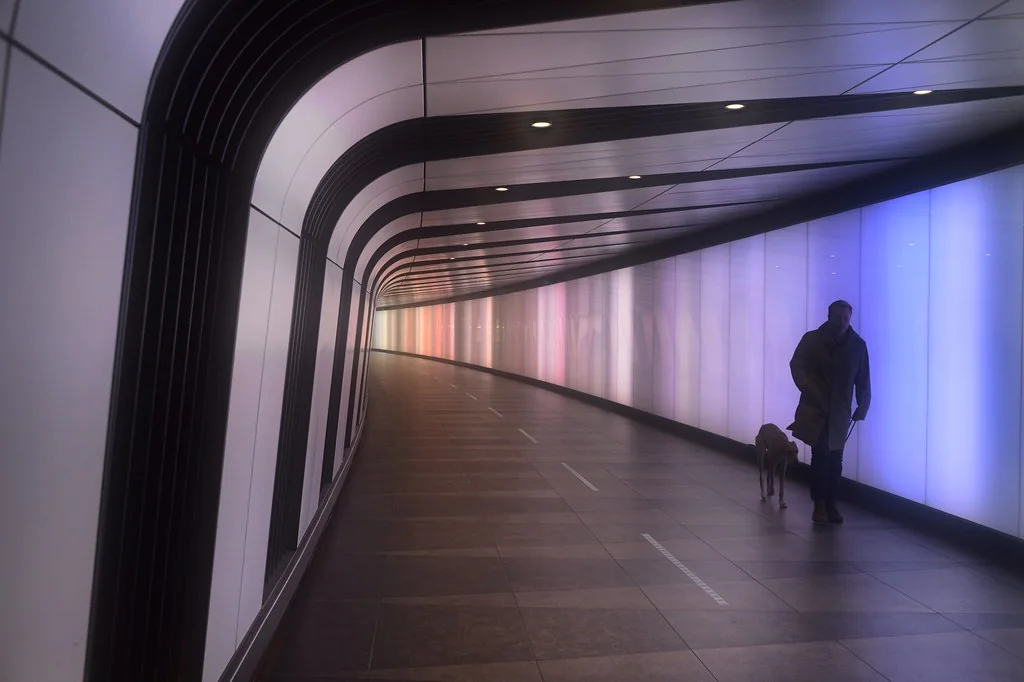 A lit pedestrian tunnel with someone walking through it